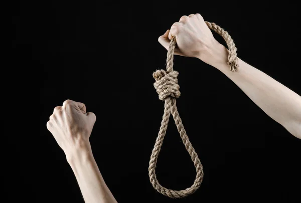 Lynčování a sebevražedné téma: izolovaná mužská ruka drží smyčku lana pro zavěšení na černém pozadí — Stock fotografie