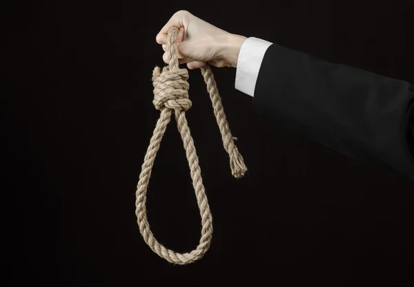 Suicide et business topic : Main d'un homme d'affaires vêtu d'une veste noire tenant une boucle de corde pour l'accrocher sur fond noir isolé — Photo