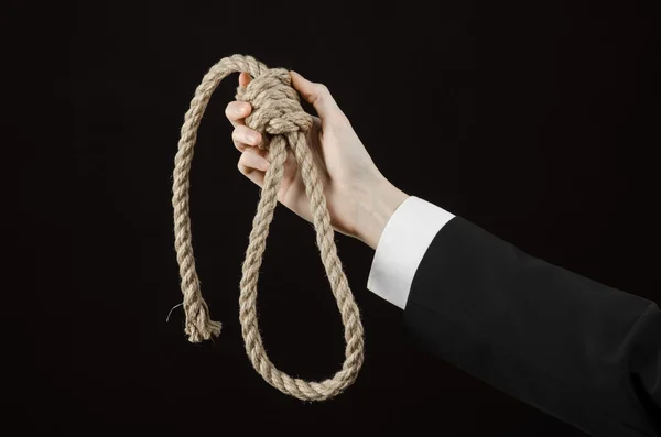 Suicidio y tema de negocios: Mano de un hombre de negocios en una chaqueta negra sosteniendo un lazo de cuerda para colgar sobre fondo negro aislado — Foto de Stock