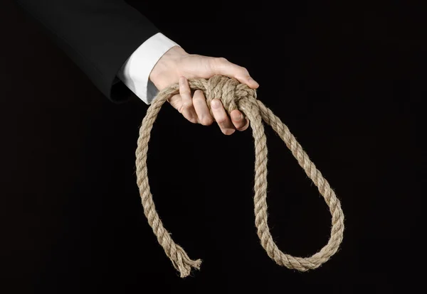 Suicide and business topic: Hand of a businessman in a black jacket holding a loop of rope for hanging on black isolated background — Stock Photo, Image