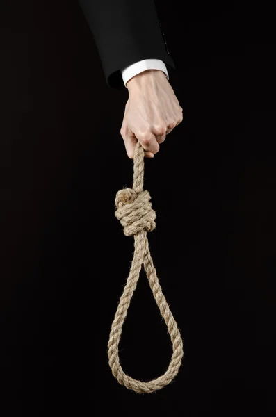 Suicide and business topic: Hand of a businessman in a black jacket holding a loop of rope for hanging on black isolated background — Stock Photo, Image