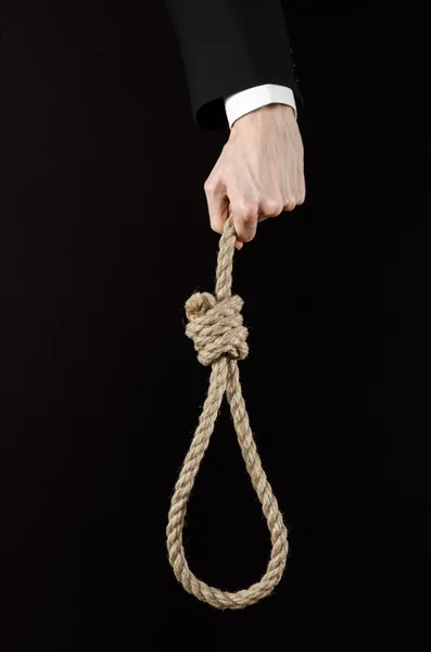 Suicide and business topic: Hand of a businessman in a black jacket holding a loop of rope for hanging on black isolated background — Stock Photo, Image