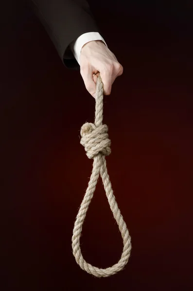 Suicide and business topic: Hand of a businessman in a black jacket holding a loop of rope for hanging on dark red isolated background — Stock Photo, Image