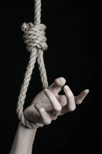 Suicide and depression topic: human hand hanging on rope loop on a black background — Stock Photo, Image