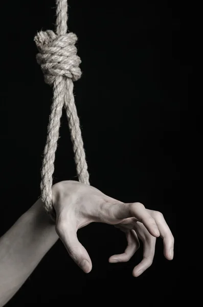Suicide and depression topic: human hand hanging on rope loop on a black background — Stock Photo, Image