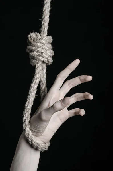 Suicide and depression topic: human hand hanging on rope loop on a black background — Stock Photo, Image