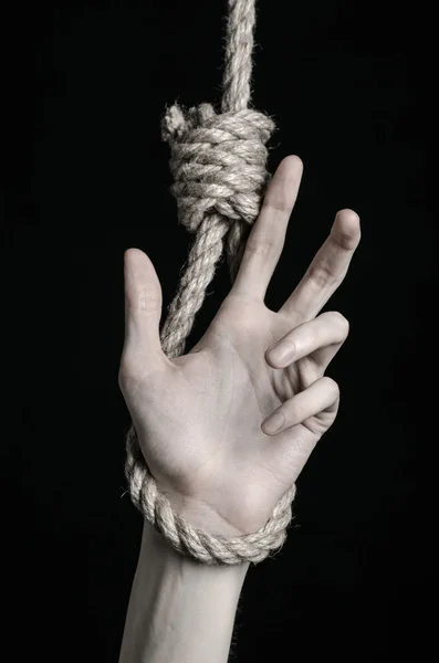 Suicide and depression topic: human hand hanging on rope loop on a black background — Stock Photo, Image