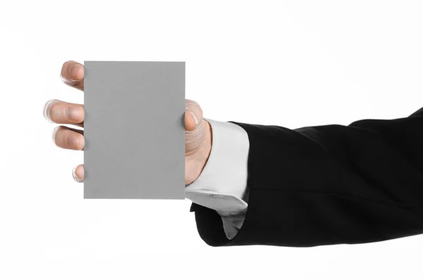 Topik bisnis dan iklan: Pria berjas hitam memegang kartu kosong abu-abu di tangan terisolasi dengan latar belakang putih di studio — Stok Foto