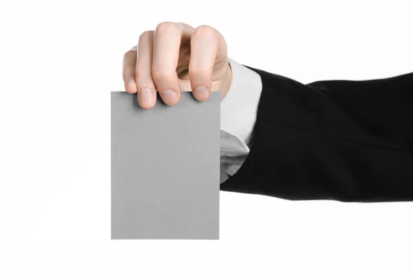 Тема бизнеса и рекламы: Человек в черном костюме, держащий в руке открытку на белом фоне в студии — стоковое фото
