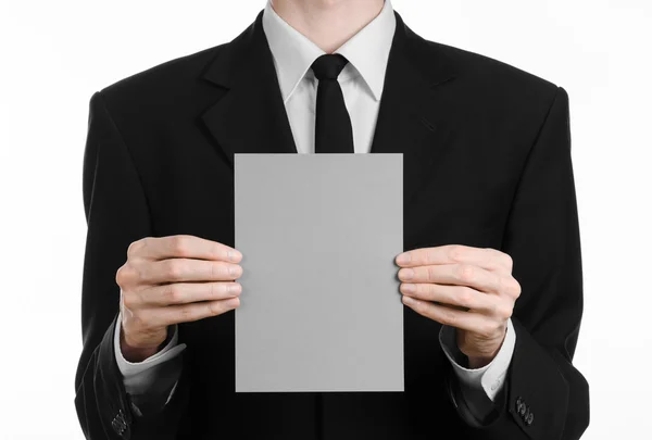 Επιχειρήσεων και διαφήμιση θέμα: άνθρωπος με μαύρο κοστούμι, κρατώντας ένα γκρι κάρτα κενό στο χέρι που απομονώνονται σε λευκό φόντο σε στούντιο — Φωτογραφία Αρχείου