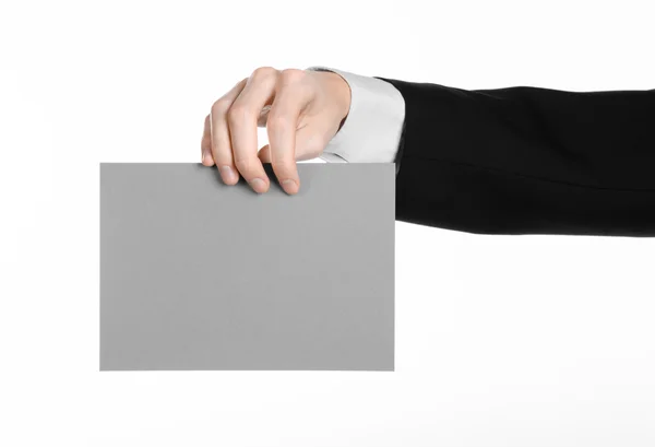 Business and advertising topic: Man in black suit holding a gray blank card in hand isolated on white background in studio — Stock Photo, Image