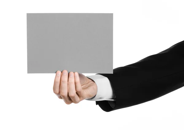 Business and advertising topic: Man in black suit holding a gray blank card in hand isolated on white background in studio — Stock Photo, Image