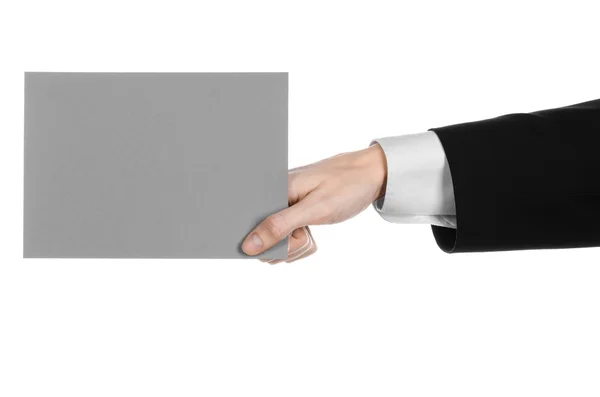 Business and advertising topic: Man in black suit holding a gray blank card in hand isolated on white background in studio — Stock Photo, Image