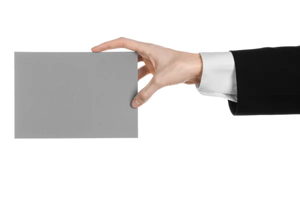 Obchod a reklama téma: muž v černém obleku drží šedou prázdnou kartu v ruce izolovaných na bílém pozadí v studio — Stock fotografie