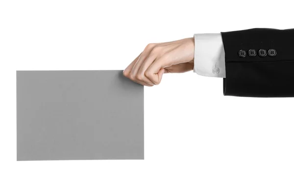 Tópico de negócios e publicidade: Homem de terno preto segurando um cartão em branco cinza na mão isolado em fundo branco em estúdio — Fotografia de Stock