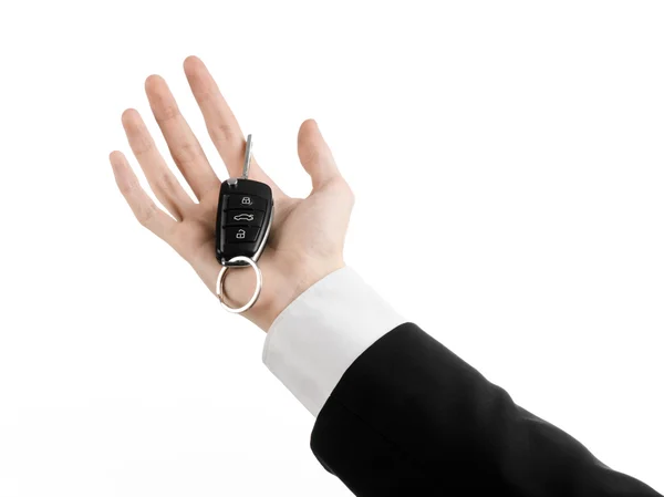 Business theme: car salesman in a black suit holding a car key isolated on white background — Stock Photo, Image