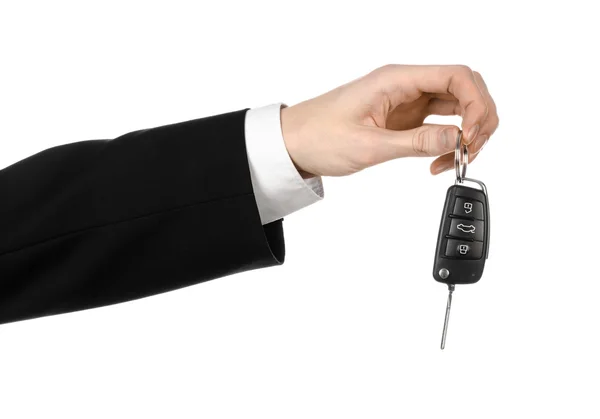 Business theme: car salesman in a black suit holding a car key isolated on white background — Stock Photo, Image
