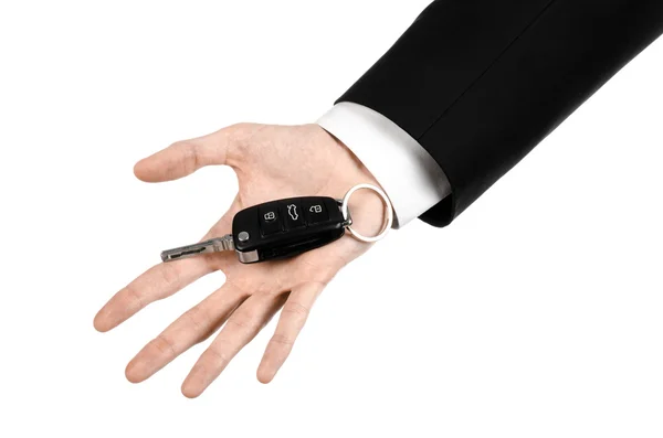 Geschäftsthema: Autoverkäufer im schwarzen Anzug mit Autoschlüssel auf weißem Hintergrund — Stockfoto