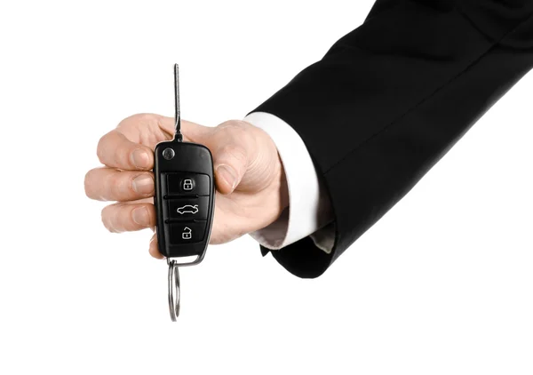 Business theme: car salesman in a black suit holding a car key isolated on white background — Stock Photo, Image