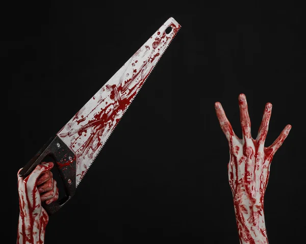 Halloween-Thema: Blutige Hand mit blutiger Säge auf schwarzem Hintergrund — Stockfoto