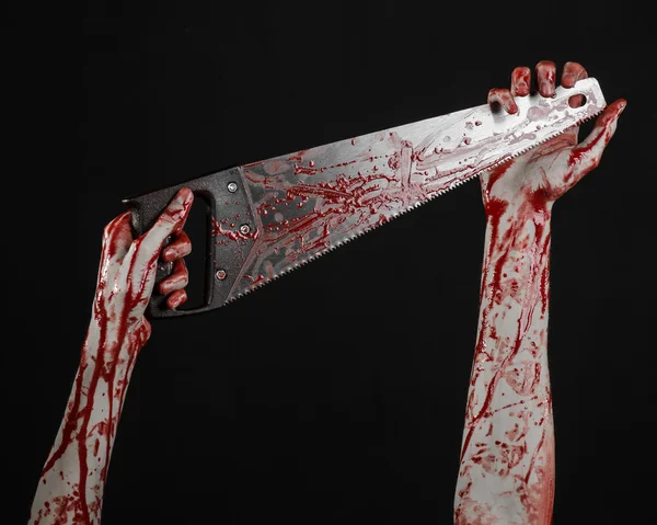 Halloween téma: krvavá ruka drží krvavého viděl na černém pozadí — Stock fotografie