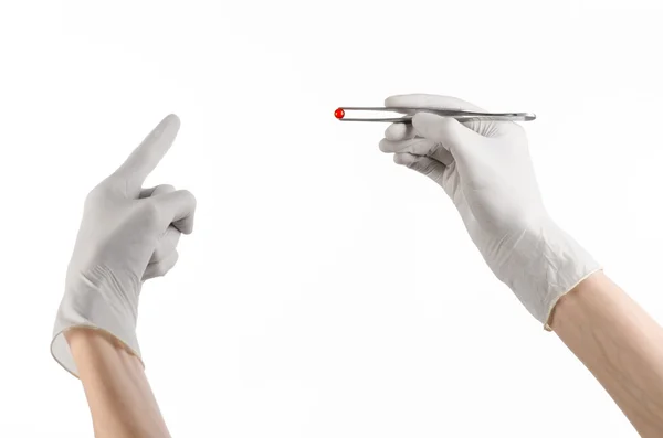 Фармакология и медицинская тема: рука врача в белой перчатке с пинцетом с капсулой красных таблеток на белом фоне в студии — стоковое фото