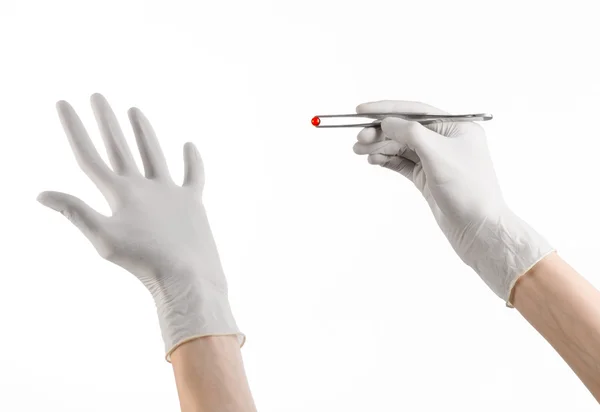 Фармакологія та медична тема: рука лікаря в білій рукавичці тримає пінцет з червоною капсулою ізольовано на білому тлі в студії — стокове фото