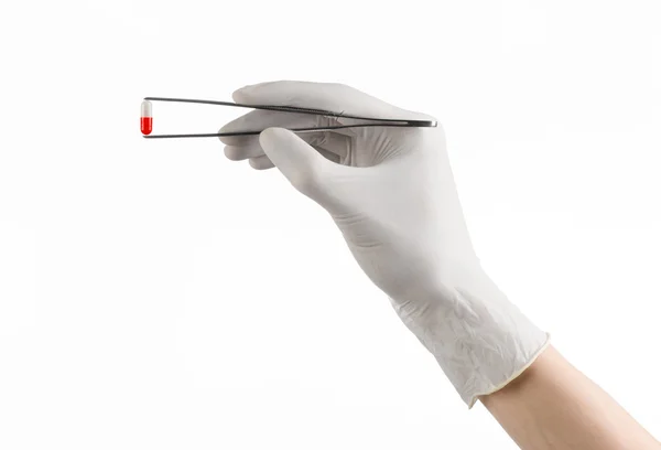 Farmacología y tema médico: la mano del médico en un guante blanco que sostiene pinzas con cápsula de píldora roja aislada sobre fondo blanco en el estudio — Foto de Stock