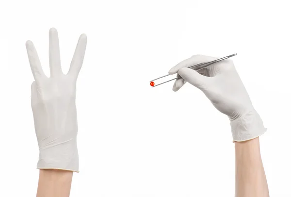 Farmakologi och sjukvård tema: läkarens hand i en vit handske holding pincett med röda pillret kapsel isolerad på vit bakgrund i studio — Stockfoto