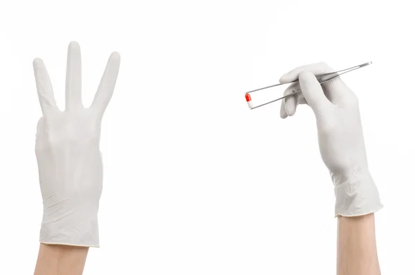 Pharmacology and Medical theme: doctor's hand in a white glove holding tweezers with red pill capsule isolated on white background in studio — Stock Photo, Image