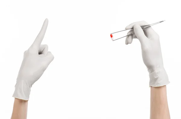 Farmakologie a zdravotní téma: za ruku v bílé rukavice drží pinzeta s červenou pilulku tobolka izolovaných na bílém pozadí v studio — Stock fotografie