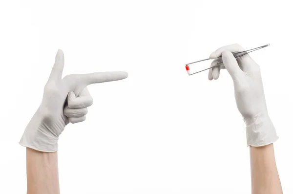 Pharmacologie et Thème médical : la main du médecin dans un gant blanc tenant une pince à épiler avec capsule rouge isolée sur fond blanc en studio — Photo