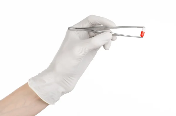 Pharmacologie et Thème médical : la main du médecin dans un gant blanc tenant une pince à épiler avec capsule rouge isolée sur fond blanc en studio — Photo