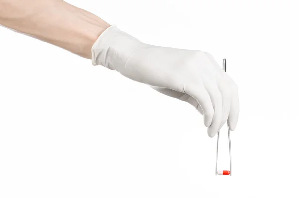 Pharmacology and Medical theme: doctor's hand in a white glove holding tweezers with red pill capsule isolated on white background in studio — Stock Photo, Image