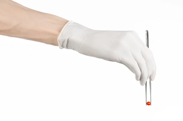 Фармакология и медицинская тема: рука врача в белой перчатке с пинцетом с капсулой красных таблеток на белом фоне в студии — стоковое фото