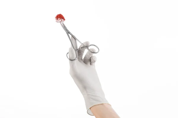 Chirurgie und medizinisches Thema: die Hand des Arztes in einem weißen Handschuh, der einen Chirurgenclip mit einem blutigen Tampon auf weißem Hintergrund im Studio hält — Stockfoto