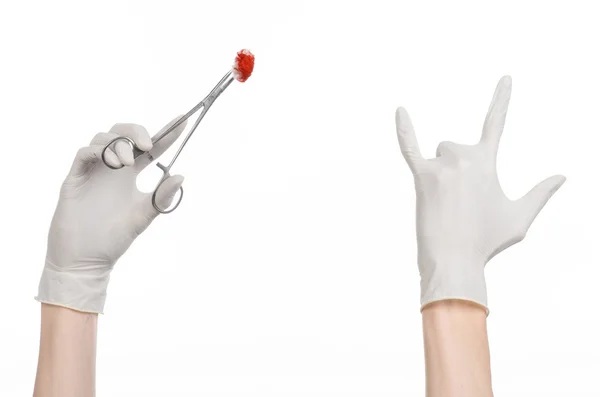Kirurgi och medicinsk tema: läkarens hand i en vit handske holding ett kirurgiskt klipp med en blodig tampong isolerad på en vit bakgrund i studio — Stockfoto