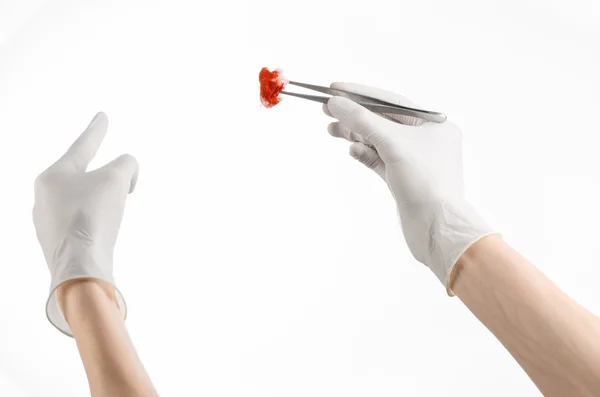 Surgery and Medical theme: doctor's hand in a white glove holding a surgical clip with a bloody tampon isolated on a white background in studio — Stock Photo, Image