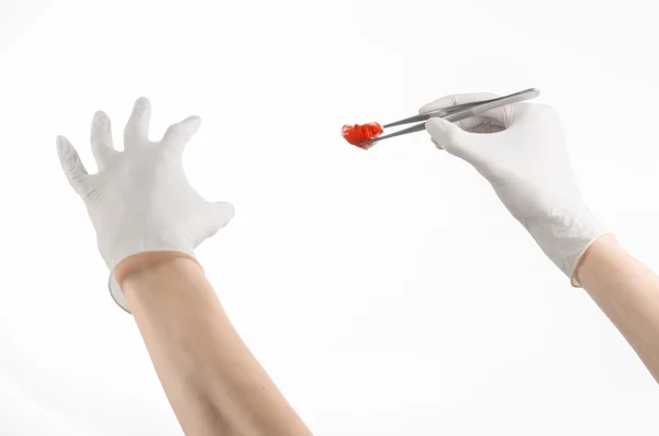 Tema Operasi dan Medis: tangan dokter dalam sarung tangan putih memegang klip bedah dengan tampon berdarah terisolasi pada latar belakang putih di studio — Stok Foto