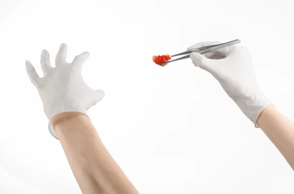 Surgery and Medical theme: doctor's hand in a white glove holding a surgical clip with a bloody tampon isolated on a white background in studio — Stock Photo, Image