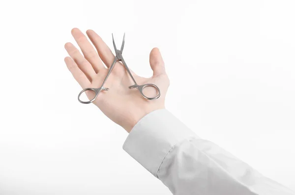 Lékařské a chirurgické téma: za ruku v bílý laboratorní plášť drží nůžky chirurgické svorky izolované na bílém pozadí v studio — Stock fotografie