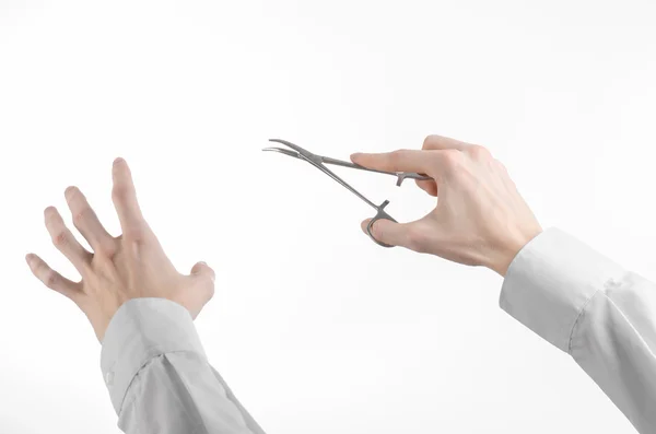 Surgical and Medical theme: doctor's hand in a white lab coat holding a surgical clamp scissors isolated on a white background in studio — Stock Photo, Image