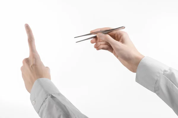 Surgical and Medical theme: a doctor's hand holding tweezers isolated on white background in studio — Stock Photo, Image