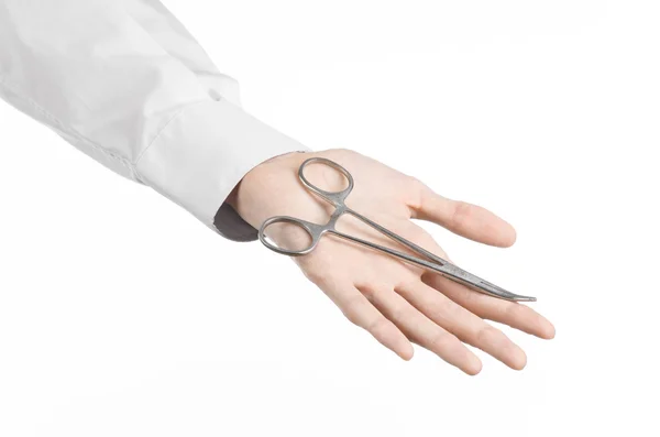 Хірургічна та медична тема: рука лікаря в білому лабораторному пальто, що тримає хірургічні ножиці для затискання ізольовані на білому тлі в студії — стокове фото