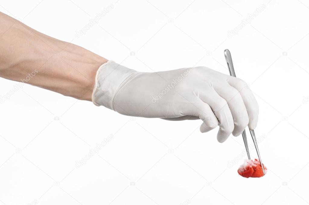 Surgery and Medical theme: doctor's hand in a white glove holding a surgical clip with a bloody tampon isolated on a white background in studio