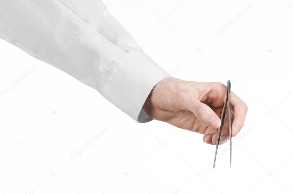 Surgical and Medical theme: a doctor's hand holding tweezers isolated on white background in studio