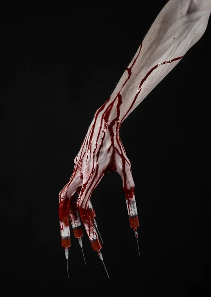 Mano ensangrentada con jeringa en los dedos, jeringas en los dedos de los pies, jeringas en las manos, horrible mano ensangrentada, tema halloween, médico zombi, fondo negro, aislado — Foto de Stock