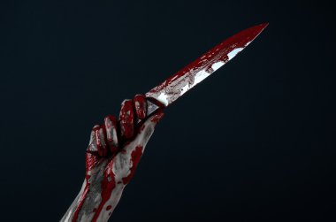 Bloody Halloween theme: zombie killer holding a large bloody knife isolated on black background in studio. clipart