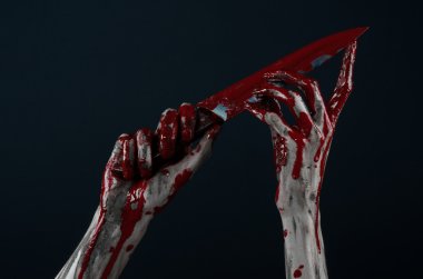 Bloody Halloween theme: zombie killer holding a large bloody knife isolated on black background in studio. clipart