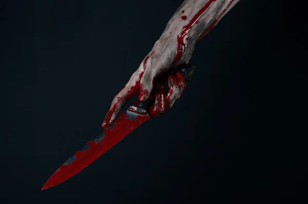 Bloody Halloween theme: zombie killer holding a large bloody knife isolated on black background in studio. — Stock Photo, Image